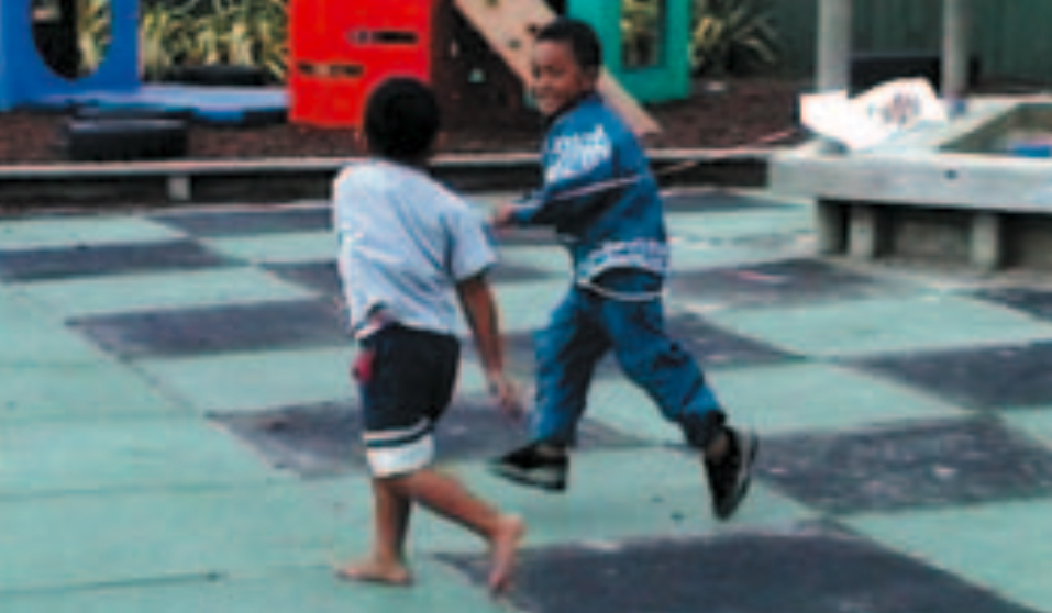 Two boys flying a kite in playground