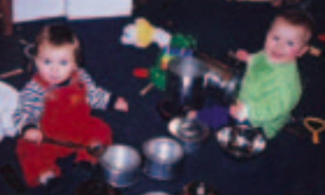 Two children banging metal bowls with a spoon