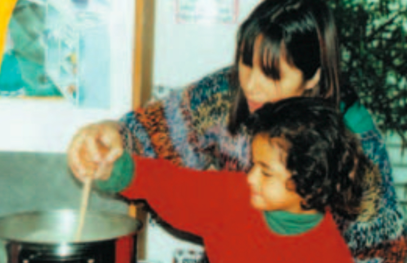 Child and teacher preparing food