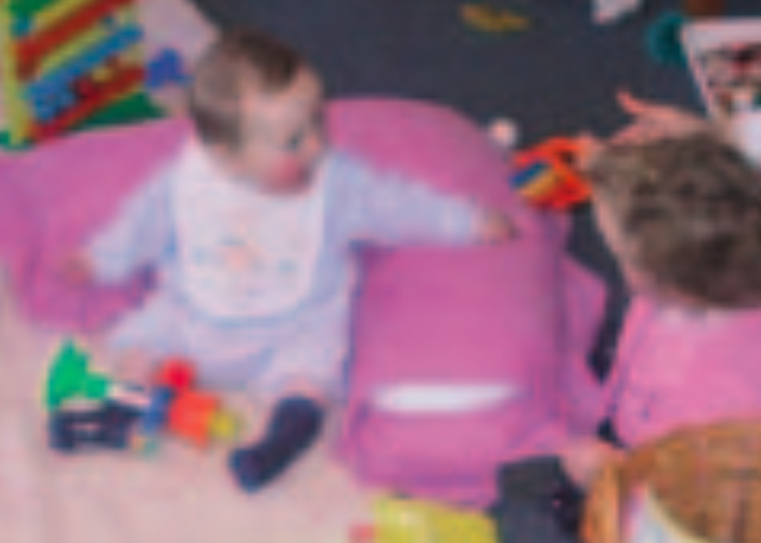 Twio infants playing on a purple cushion