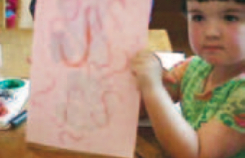Infant girl holding up drawing
