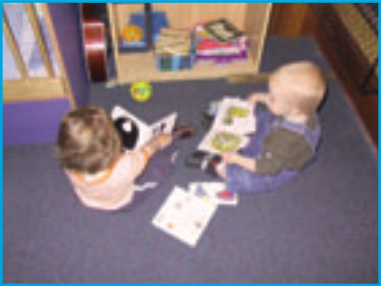 Two infants looking at picture books