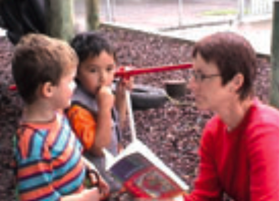 Two children and teacher reading a book