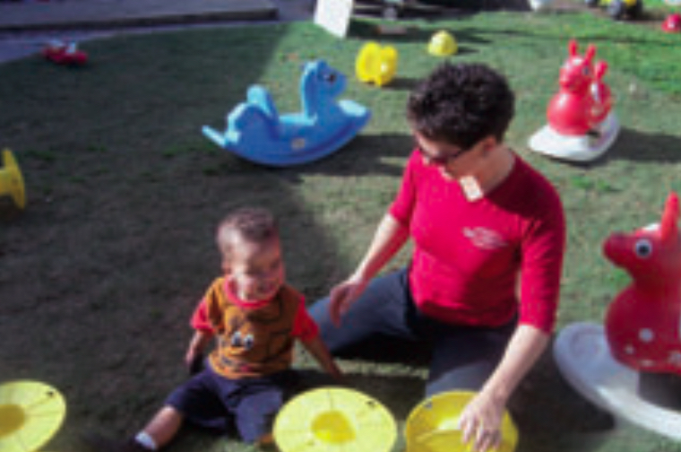 Child and teacher playing with yellow plastic reels