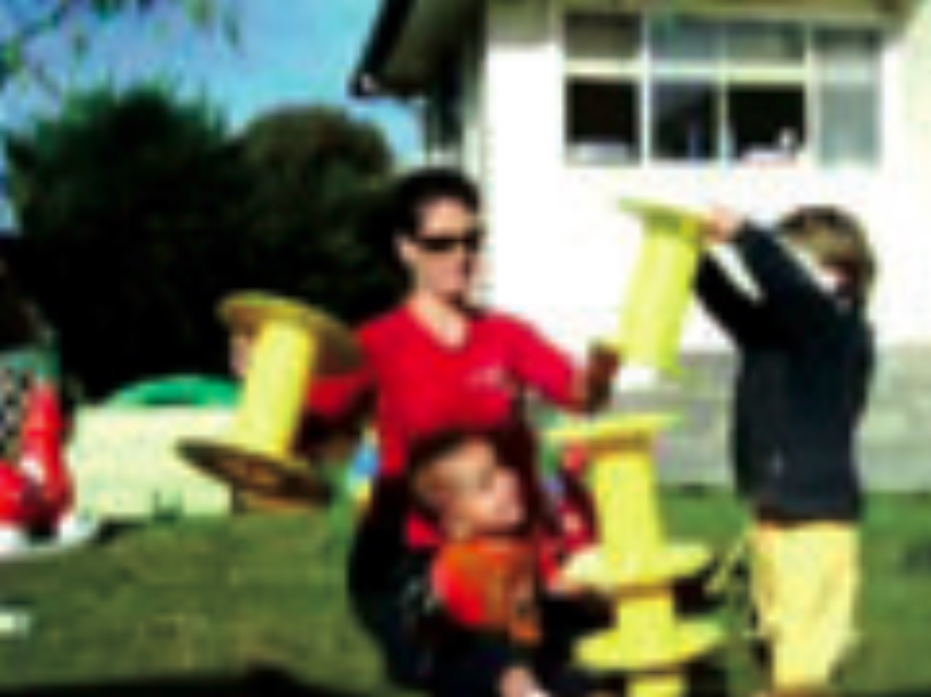 Children and teacher playing with yellow plastic reels