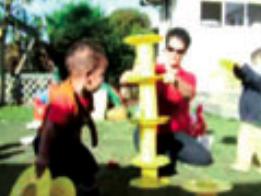 Children and teacher playing with yellow plastic reels