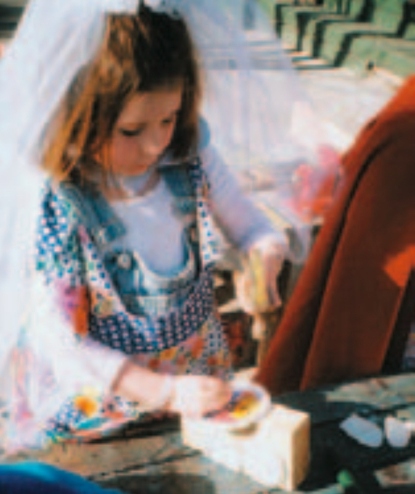 Auburn-haired girl wearing wedding veil creating a picture of a bus