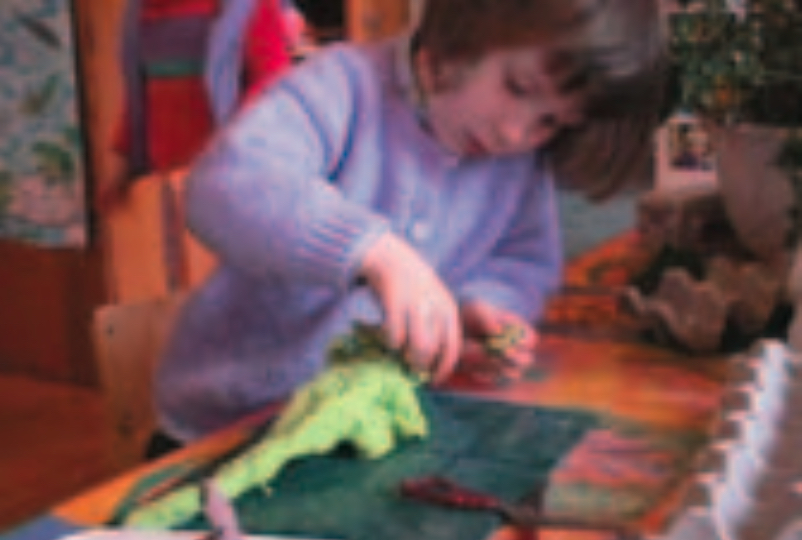 Girl making a green play-dough dinosaur