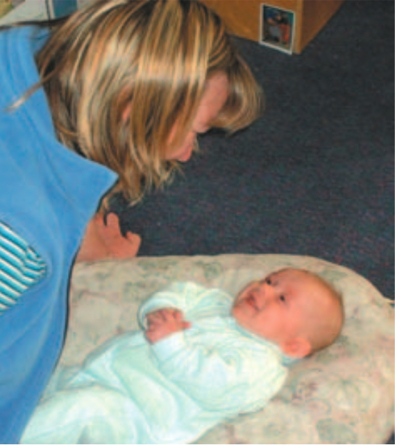 Blond woman looking down at a baby on a blanket
