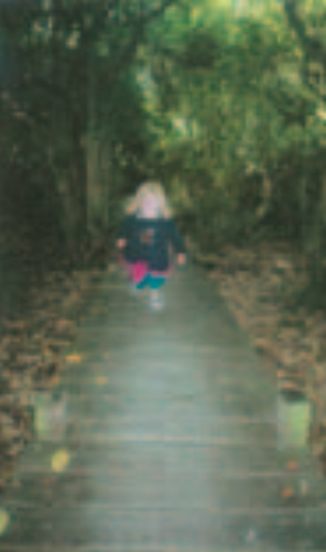 Blonde girl walking down wooden path