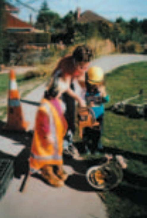 Two children wearing safety gear, being attended by an adult