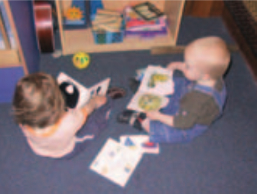 Two infant boys looking at books