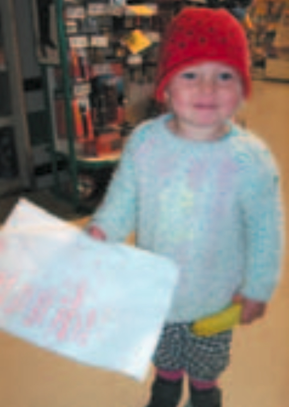 Infant girl wearing red beanie holding a shopping list written in red ink