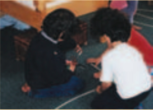 Child sticking masking tape to floor