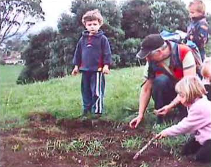 Children and adult digging in a field